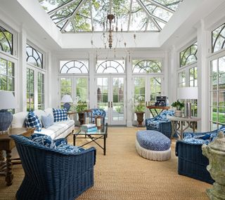 sunroom with vaulted ceiling, glass windows and doors, blue and white furniture, coir flooring