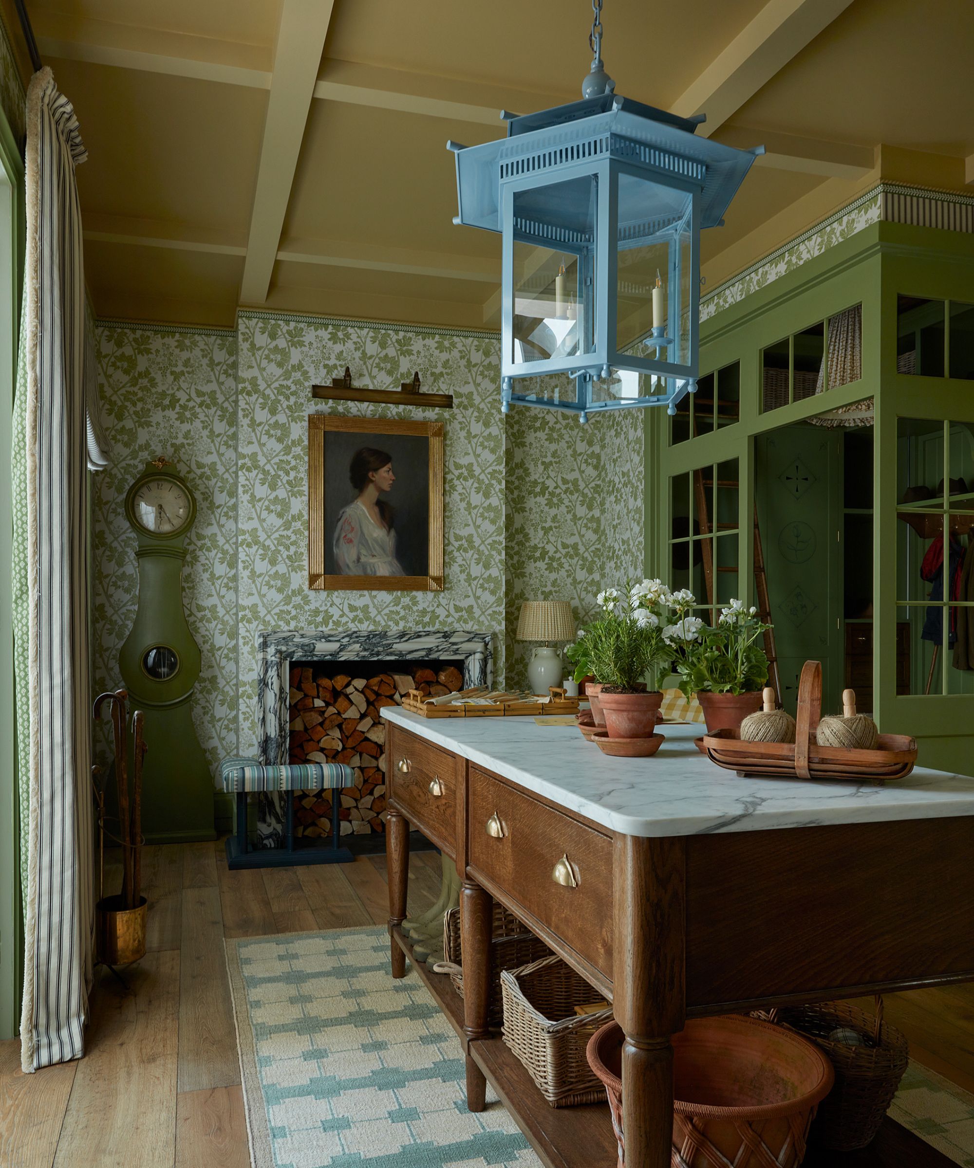 A traditional kitchen with a cook's table and green floral wallpaper