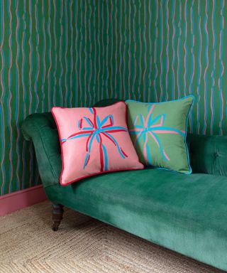 Common Room bow design screen printed cushion on green chaise with green wallpaper
