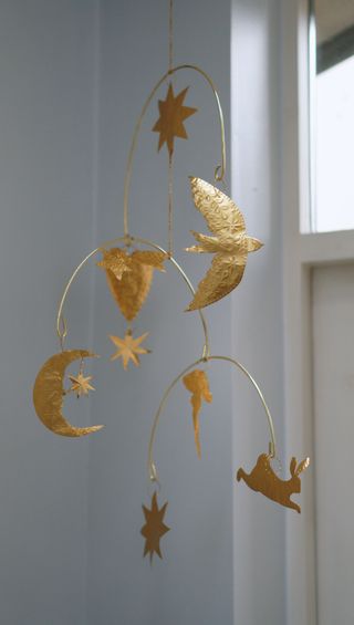 Gold ornament mobile hanging in a white corner of a room