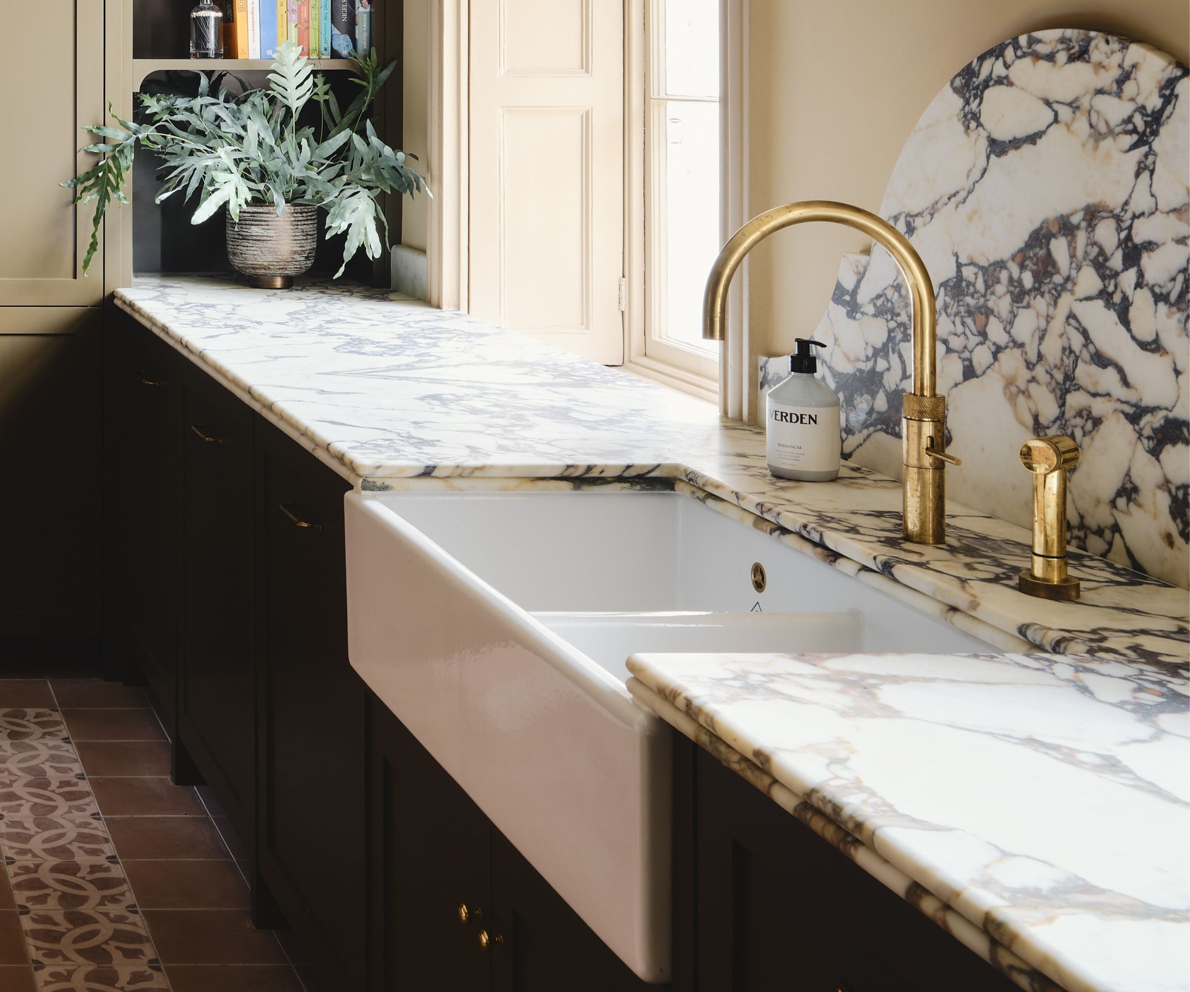 A green kitchen with marble countertops featuring a double bullnose edge profile