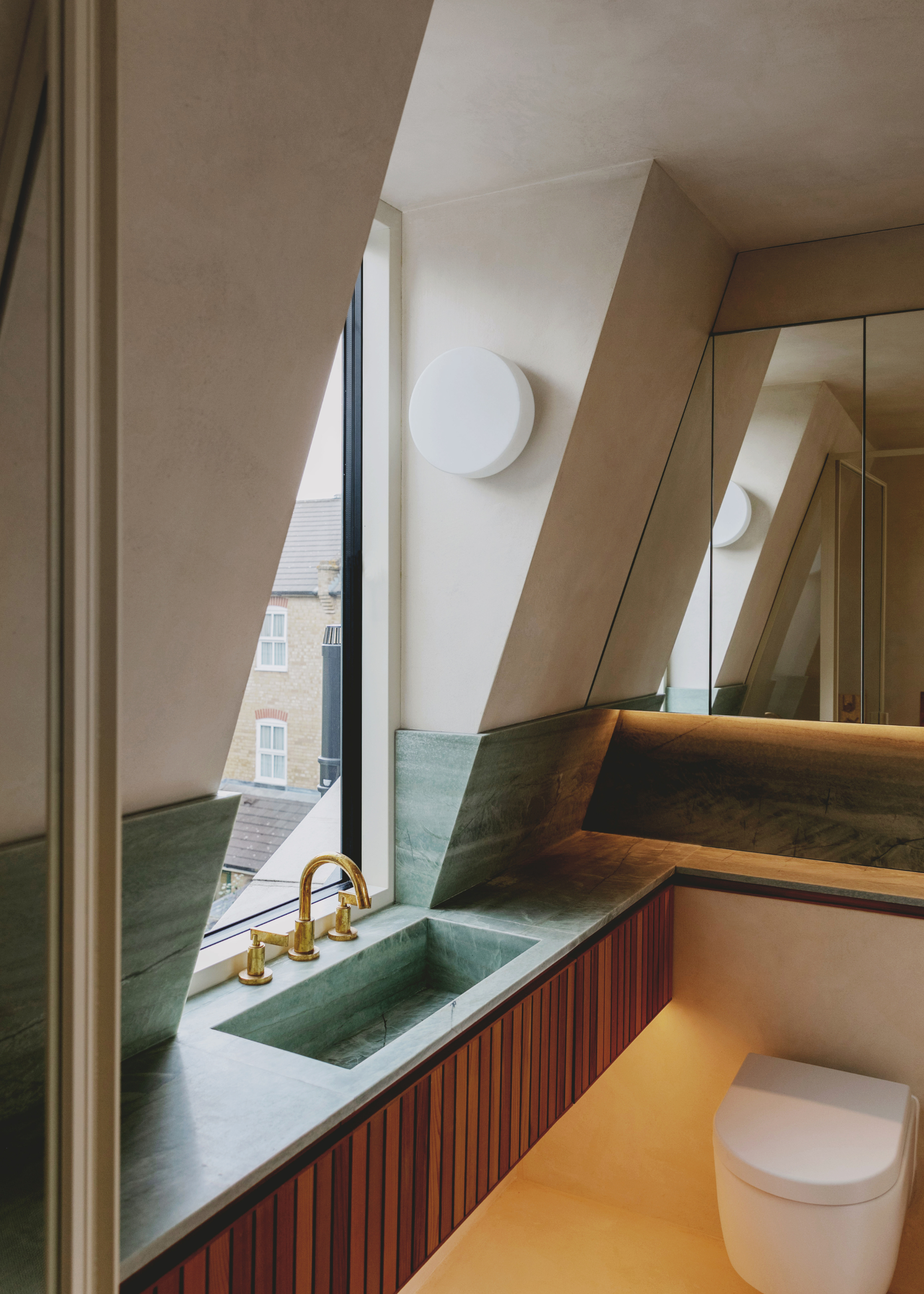a small loft conversion ensuite with green marble counters and ribbed wood cabinets
