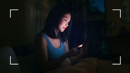 Woman sitting on phone in the middle of the night, wondering how to get back to sleep