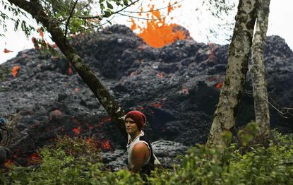 A lava fissure erupts as a resident stands nearby in the aftermath of eruptions from the Kilauea volcano on Hawaii's Big Island, on May 12, 2018 in Pahoa, Hawaii.