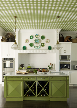 A green kitchen with a green island, a green and white checkered ceiling and green plates hanging on the wall