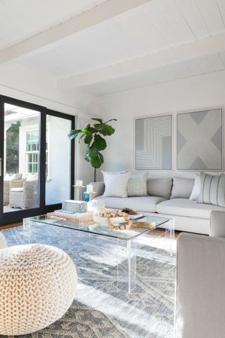 White living room with grey patterned rug, clear coffee table and light gray sofa