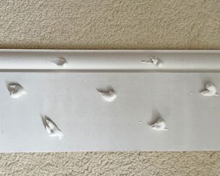 blobs of grab adhesive on a piece of primed skirting board