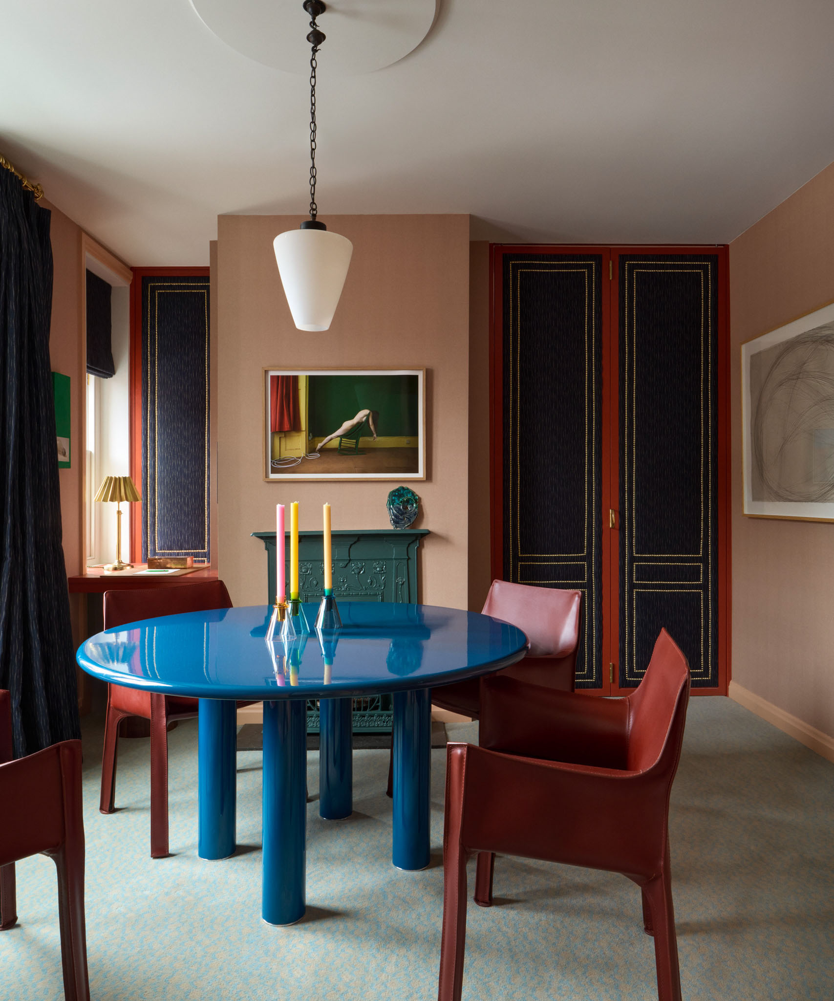 A contemporary dining room with blue lacquer table and red leather chairs