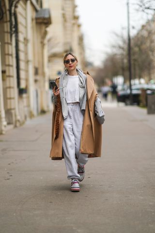 woman wearing white t-shirt, sweatpants, and a trench coat