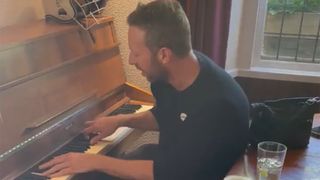 Chris Martin playing piano in pub