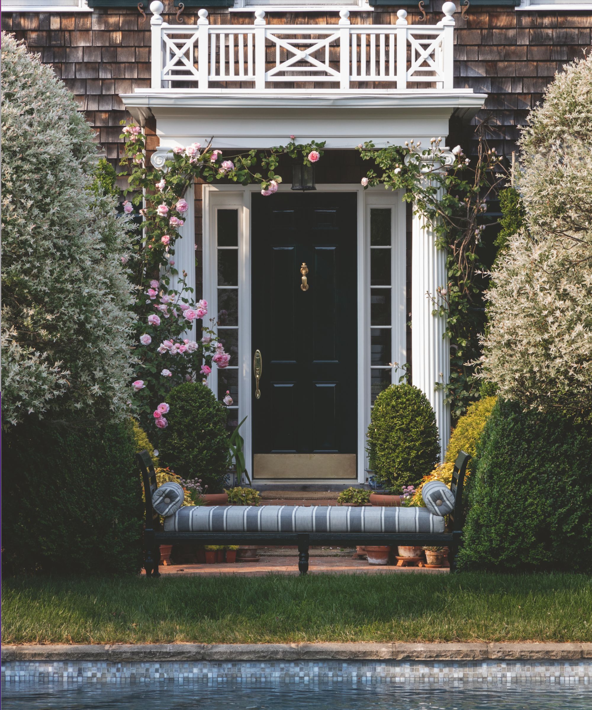 Front door leading to a garden with a rambling rose and a garden bench