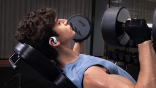 Shokz OpenFit Air 2 wireless earbuds in white being worn by a man working out at the gym