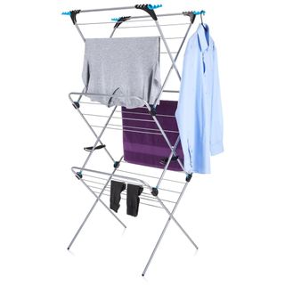 A clothes airing rack with a grey top, two black socks, a purple towel and blue shirt hanging on it