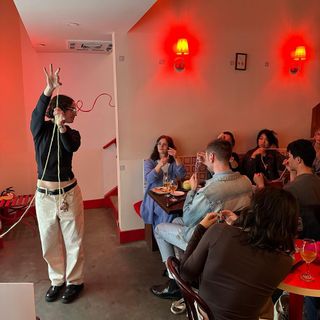 Ella Emhoff holding yellow yarn and teaching to a crowd of people at a Soft Hands Knit Club event