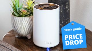 A TP-Link Deco XE75 mesh router on a table with a Tom's Guide Price Drop deals badge on top
