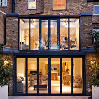 Evening time outside a double storey glass conservatory extension of a townhouse