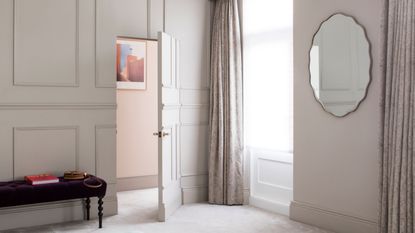 Dressing table in a grey alcove with circular wall mirror, fur topped stool