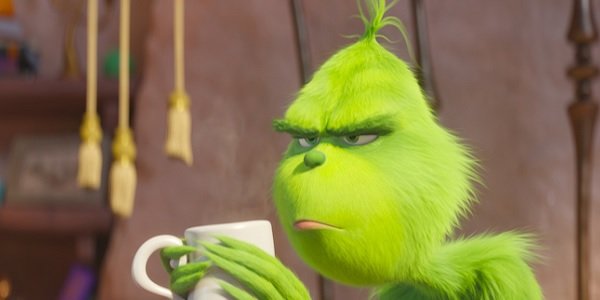 The Grinch has a cup of coffee with a scowl on his face