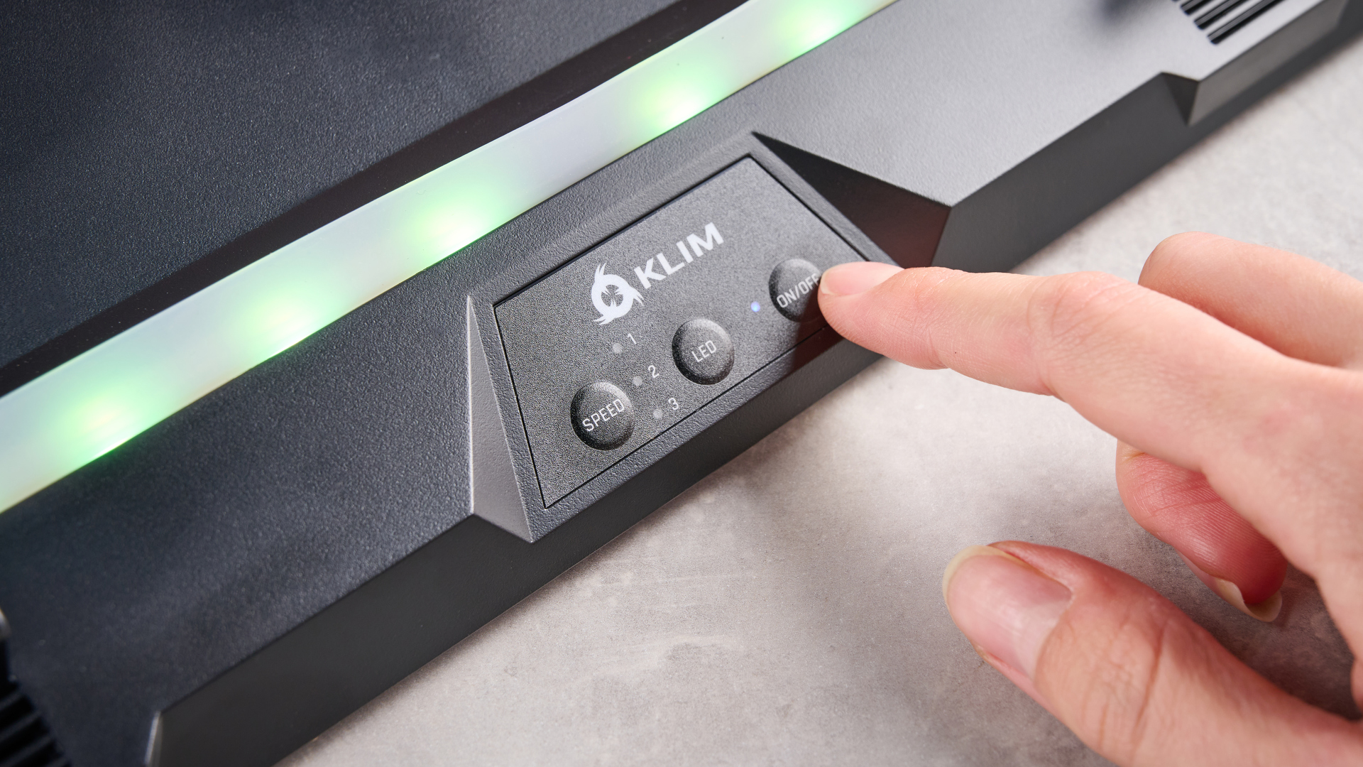 A close-up of the controls at the front of the Klim Mistral laptop cooling pad, featuring three buttons marked Speed, LED and On/Off &amp;ndash; a finger hovers over the On/Off button.
