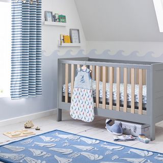 Nursery with blue striped curtain, blue boats rug and blue cot bed