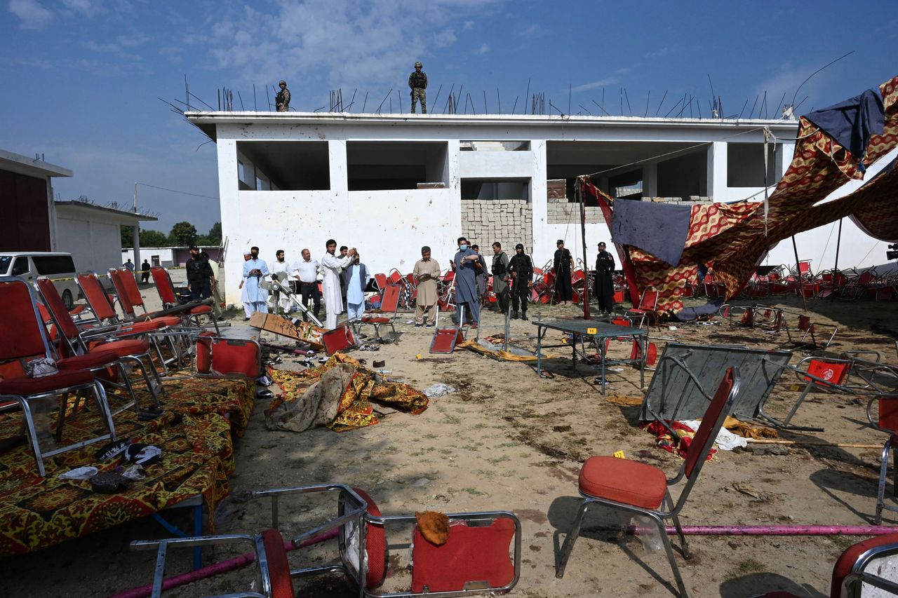 People walk around a blast site in Pakistan