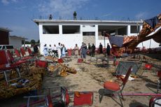 People walk around a blast site in Pakistan