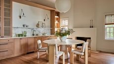 Dining room with wood floor, wood cabinets, round dining table and boucle chairs and lantern light