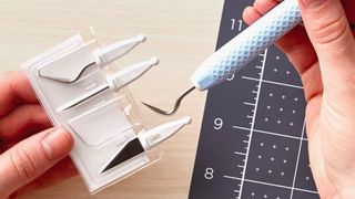 The best Cricut accessories; a close up of a person removing a weeding tool from a Cricut tool kit