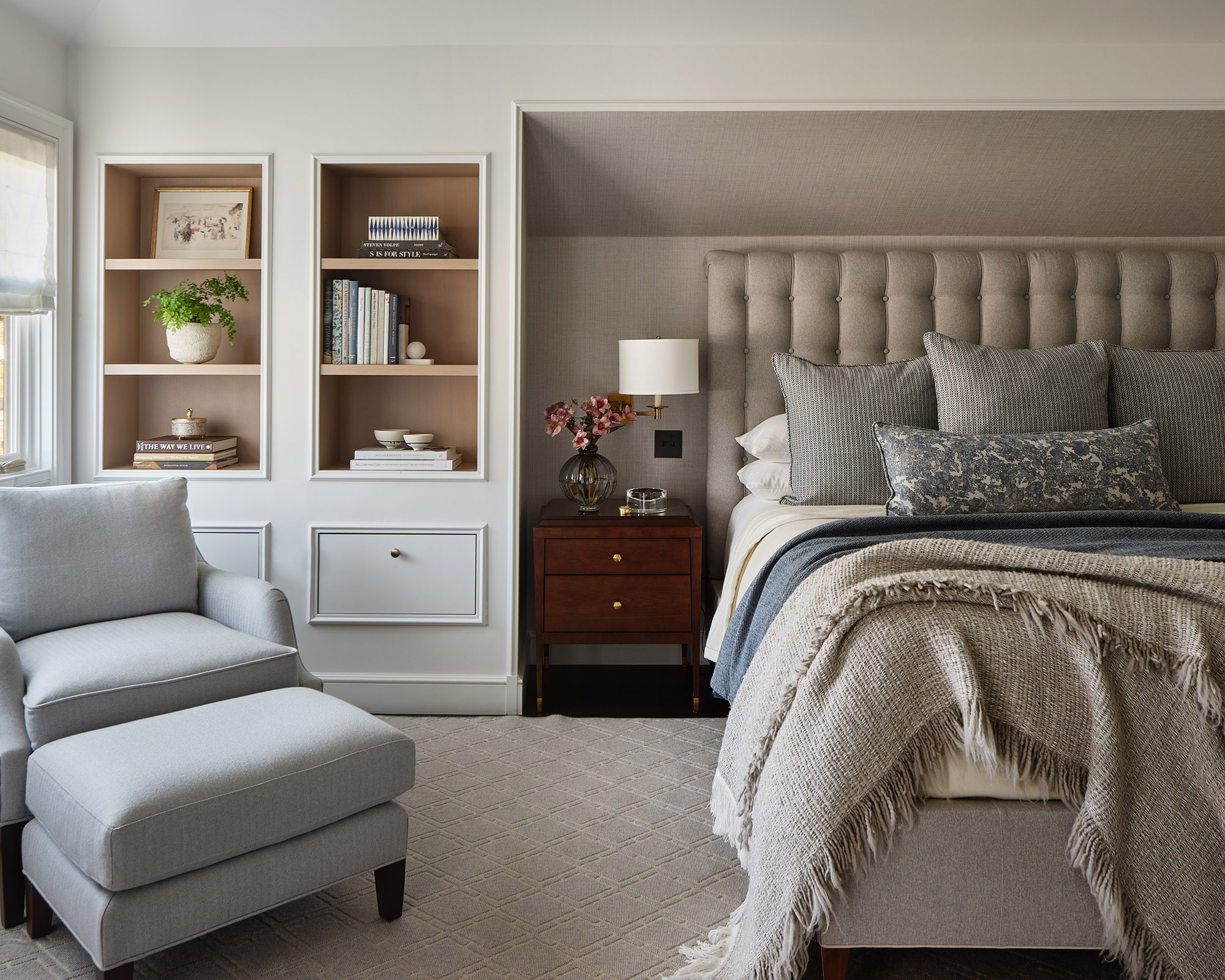 gray bedroom with large gray armchair and lots of gray pillows on the bed