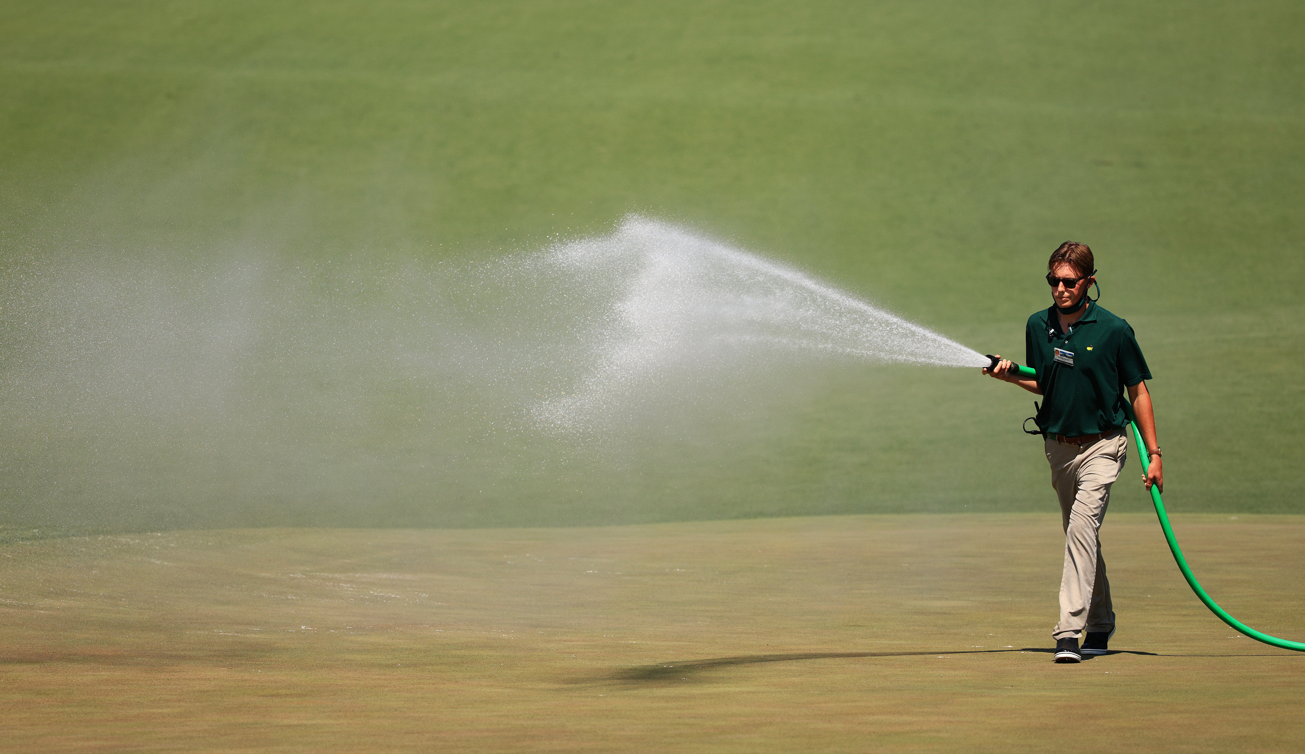 A greenskeeper sprays water during a practice round prior to the Masters at Augusta National Golf Club