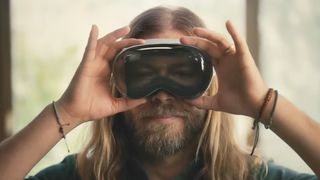 A screenshot from the advert for the Apple Vision Pro, showing a man holding on to one like goggles