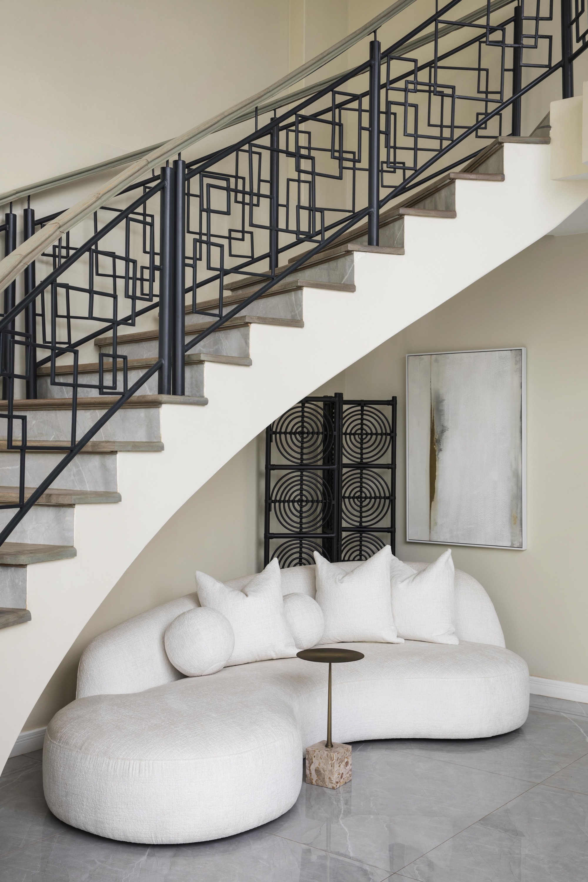 modern staircase with architectural balustrade, gray tiles, curved white sofa with small side table