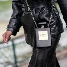 A woman wearing a leather outfit with a Chanel No5 handbag, one of the top perfumer fragrances