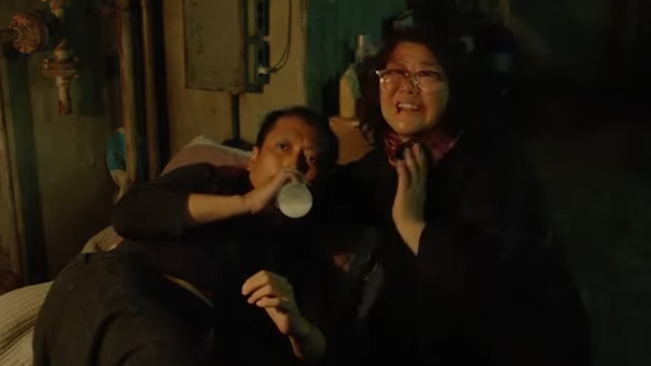 Park Myung-hoon drinking a beverage while Lee Jung-eun stays by his side in Parasite