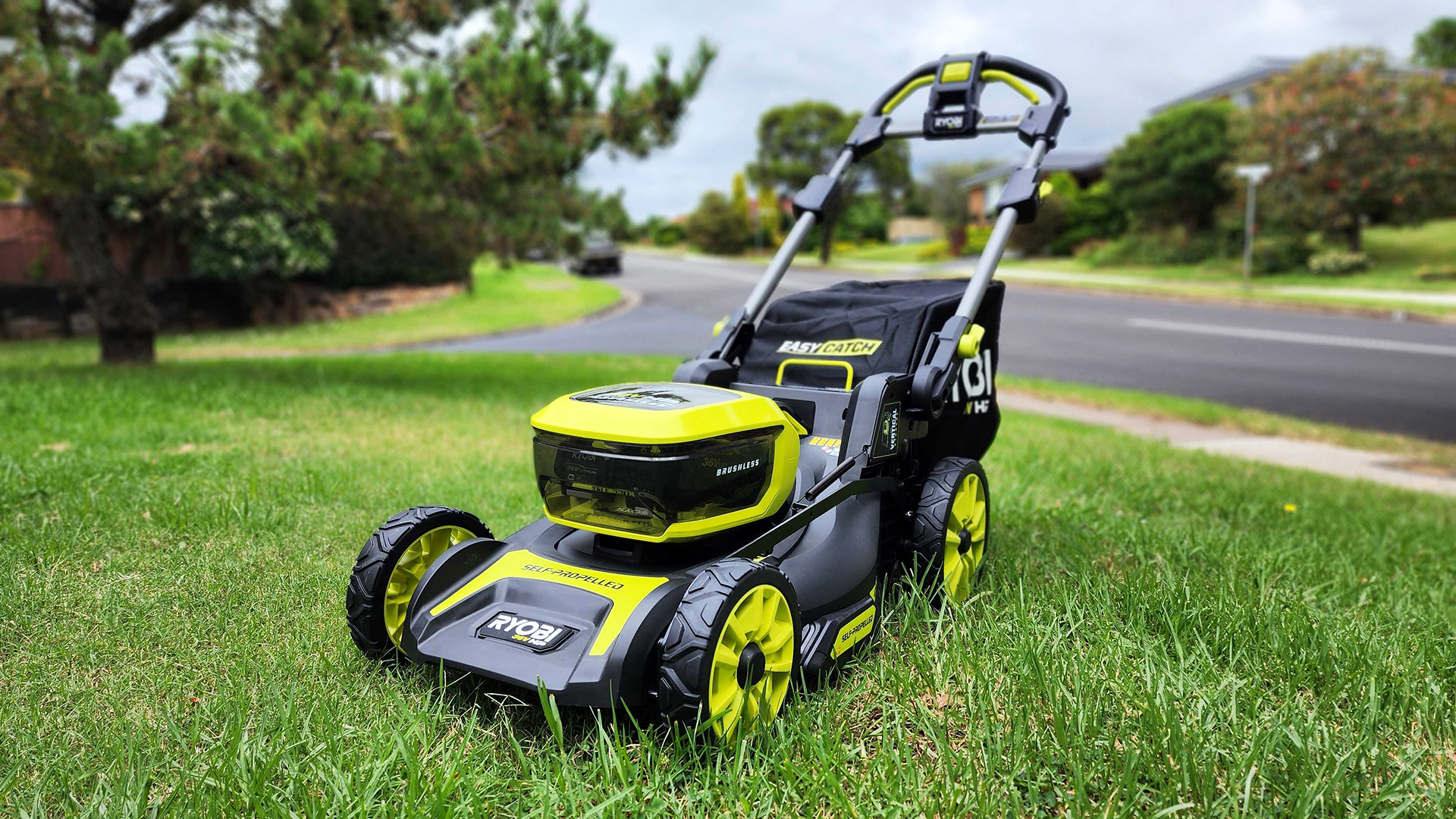 Ryobi 36V HP 46cm 6.0Ah Brushless Cordless Lawn Mower on a lawn with street in the background