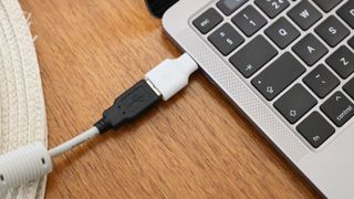Close up of a USB cable and adapter in the port of a MacBook Pro laptop