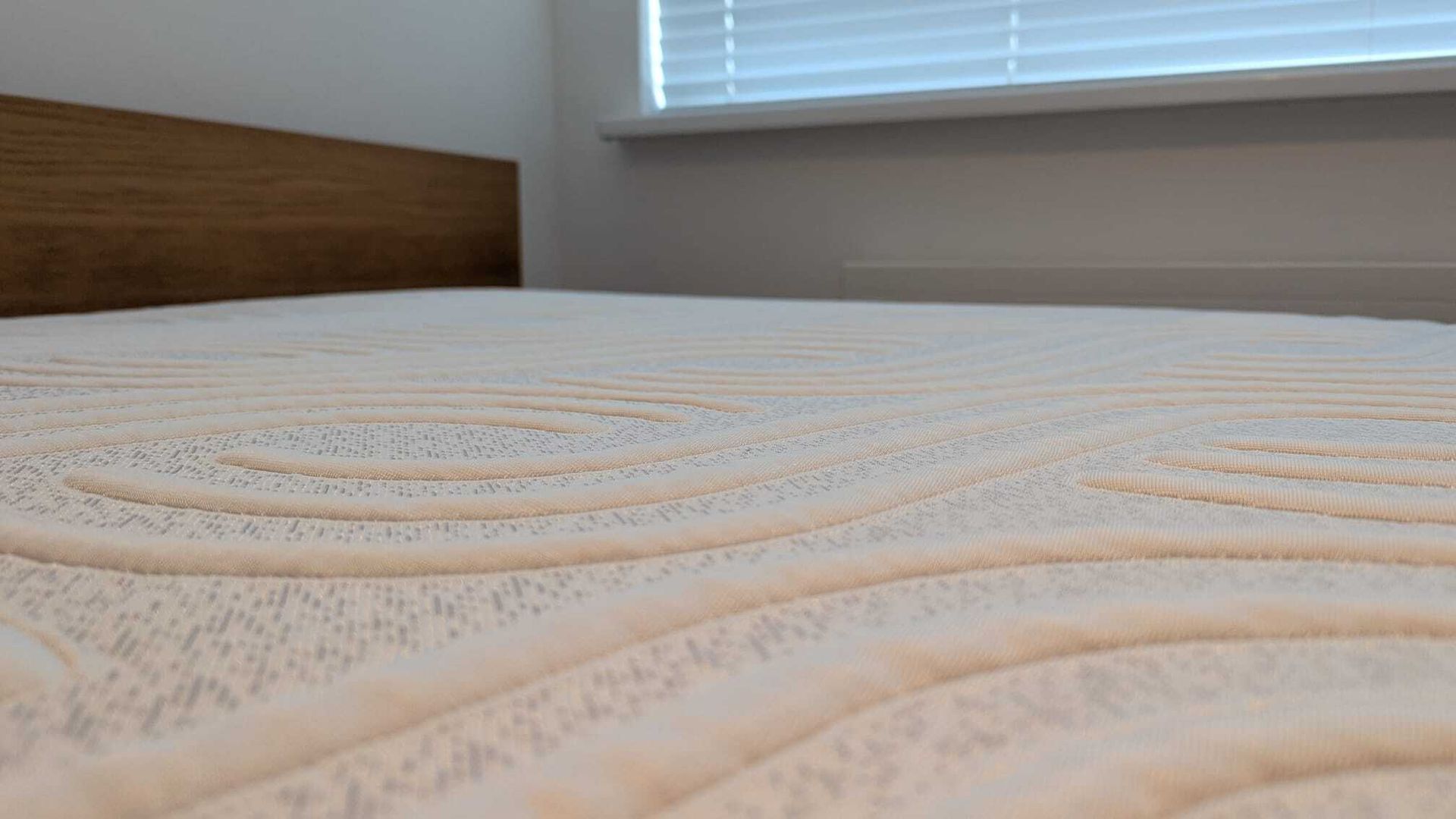 The image shows a dark haired woman vacuuming a white mattress to remove dust mites