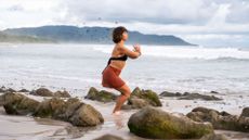 woman on beach doing standing yoga