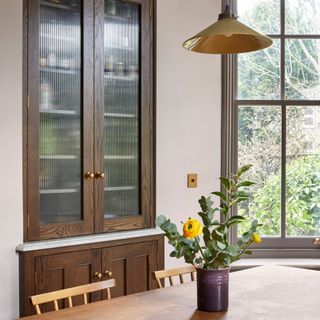 a kitchen diner with built in dark wooden cabinet with fluted glass doors