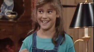 Alyssa Milano smiling with an aqua shirt and overalls on in Who's The Boss