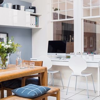 White desk under window in a blue dining room