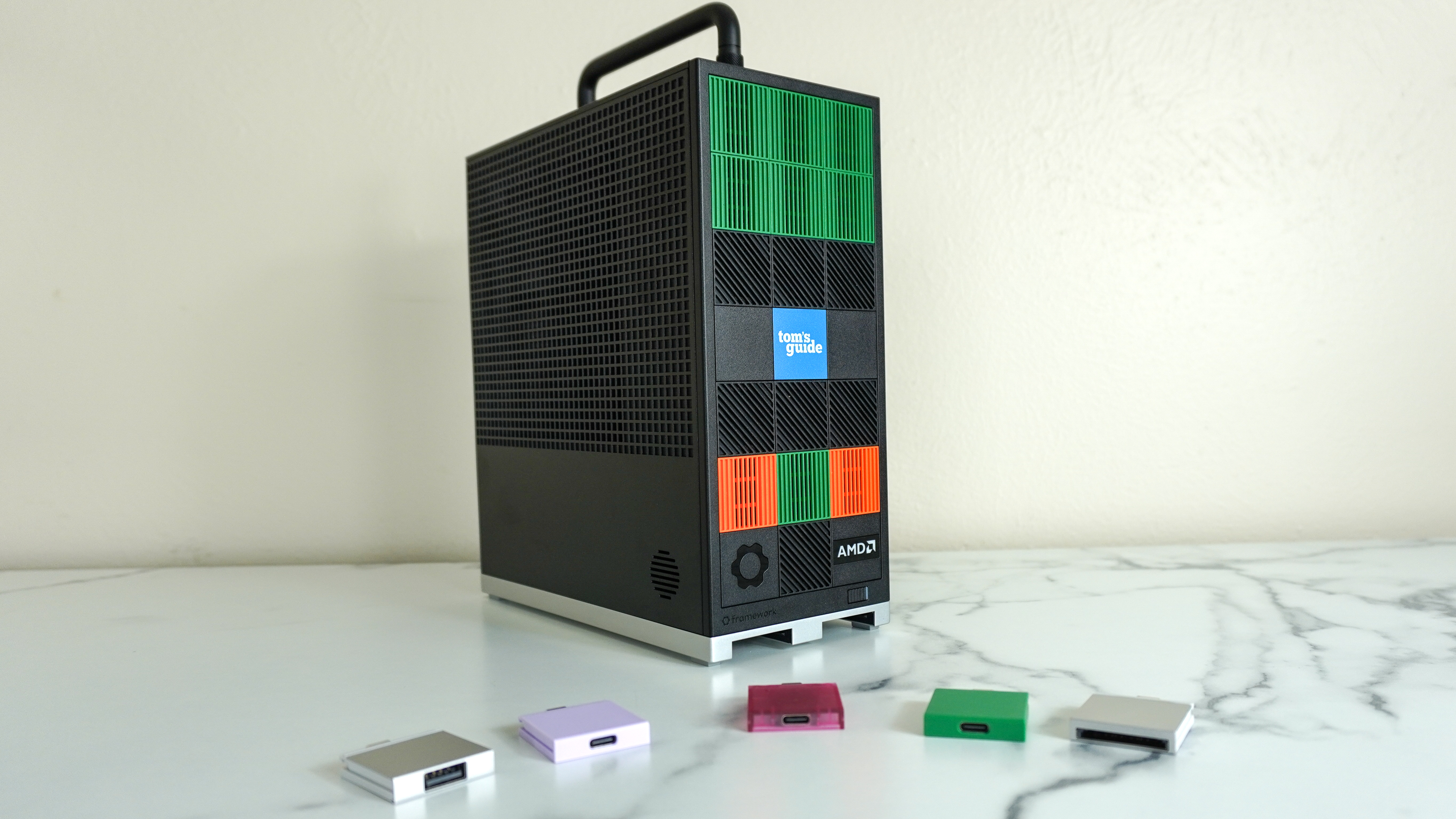 The Framework Desktop on a desk with several Expansion Cards in front of it