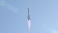 a white rocket launches into a blue sky