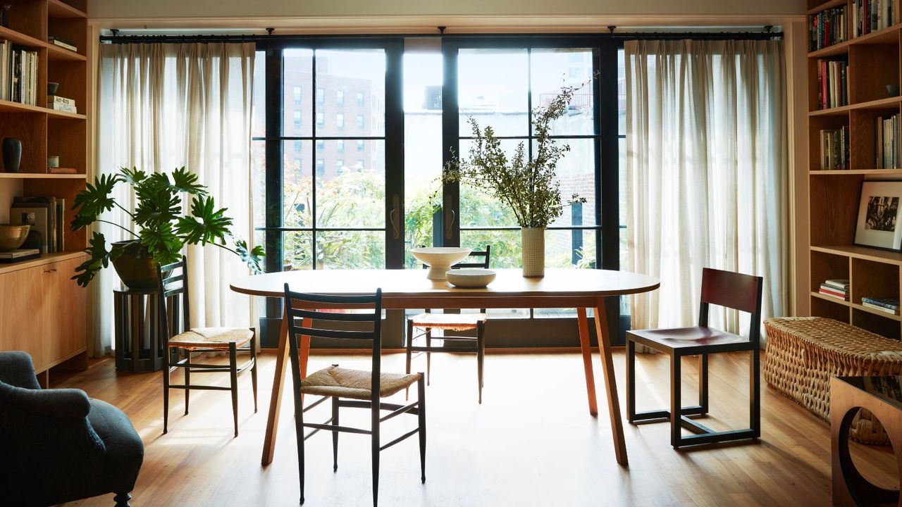 dining room with wooden floor and oval table with shelving unit and picture windows