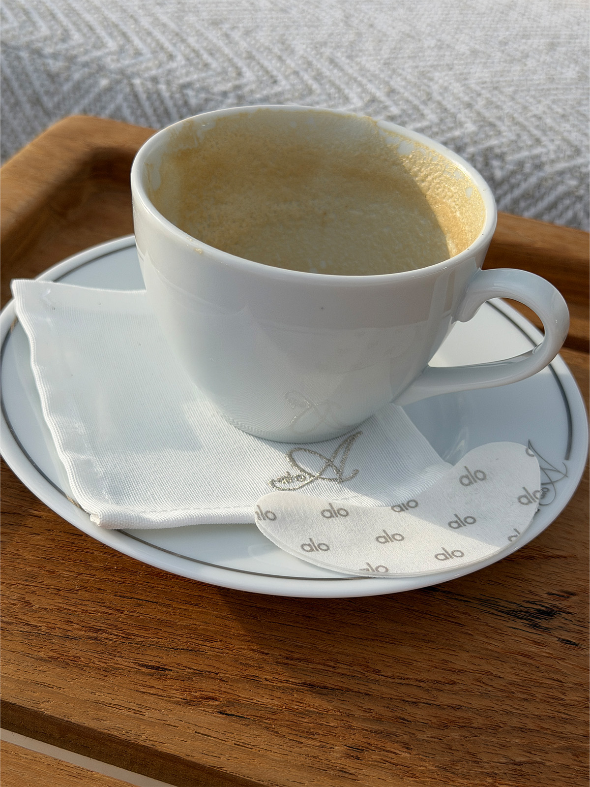A coffee cup with Alo under-eye masks on the plate.