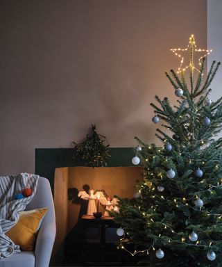 Christmas tree with ornaments by fireplace