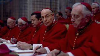 a room of cardinals in a row, all in red robes