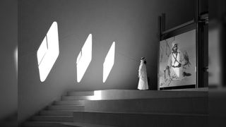 Modern interior with geometric lights and a person viewing a large monochrome photograph