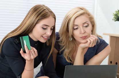 Mother and daughter shopping online together. Girl holding credit card ready to buy something. E-commerce and online shopping consept.