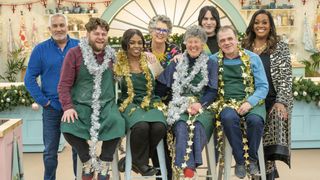 Paul Hollywood, Dame Prue Leith, Noel Fielding and Alison Hammond stand behind Mark, Maxy, Maggue and Jurgen who are wearing tinsel and stars in the tent in The Great British Bake Off.
